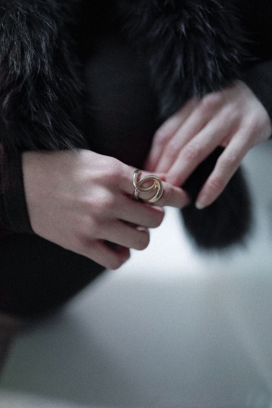 Close-up of female hands adorned with a gold ring and elegant fur coat, showcasing fashion accessories.